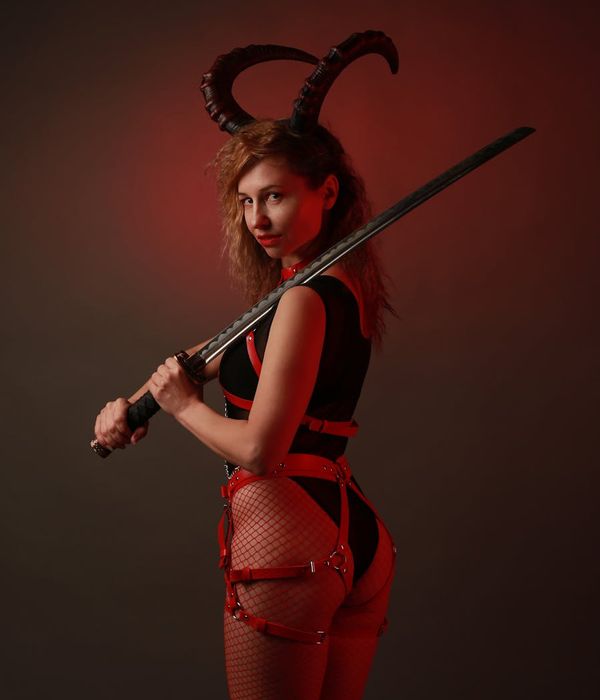 Woman in a strong warrior yoga pose against a dark background.